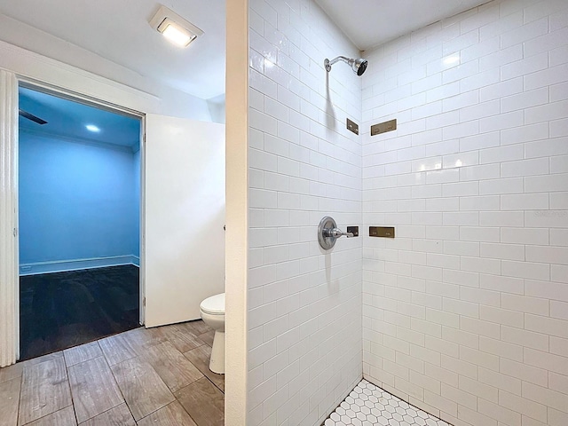 bathroom with a tile shower, wood finish floors, and toilet