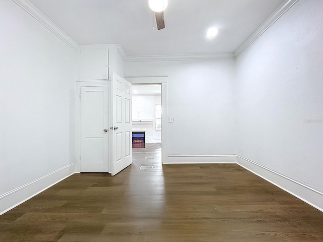 unfurnished room featuring crown molding, a warm lit fireplace, and baseboards