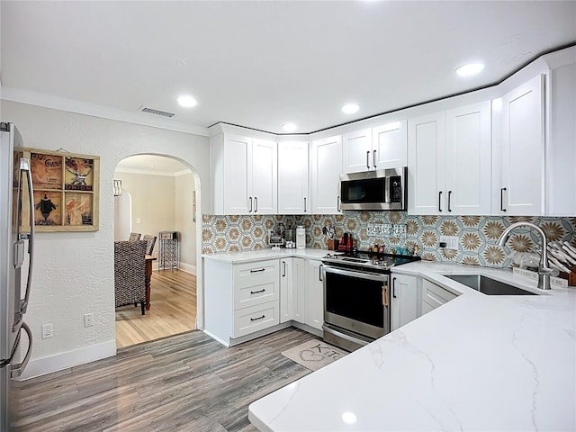 4231 8th St N, Saint Petersburg, FL 33703 - kitchen featuring a sink, stainless steel appliances, visible vents, light stone countertops, and arched walkways