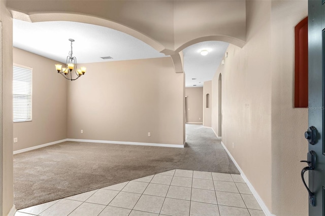 interior space featuring visible vents, light colored carpet, arched walkways, light tile patterned floors, and a notable chandelier