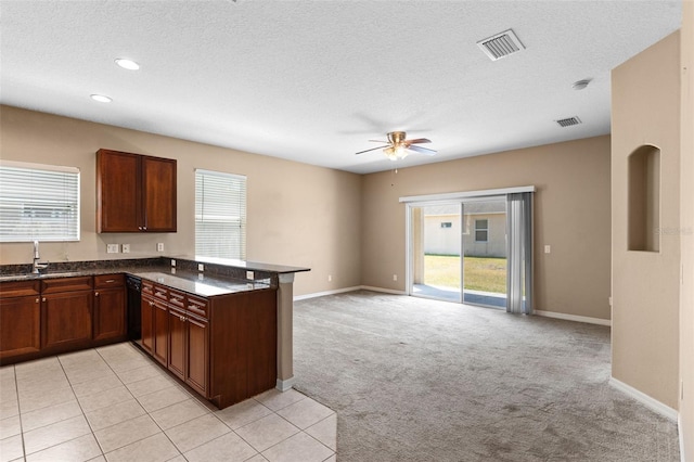 kitchen with ceiling fan, dark countertops, a sink, dishwasher, and visible vents