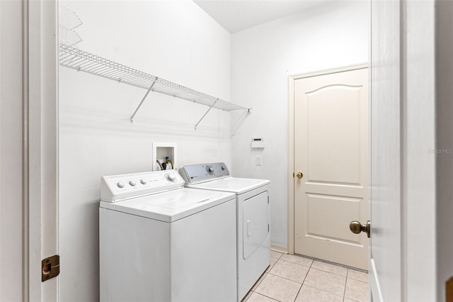 clothes washing area featuring light tile patterned floors, baseboards, laundry area, and washing machine and clothes dryer