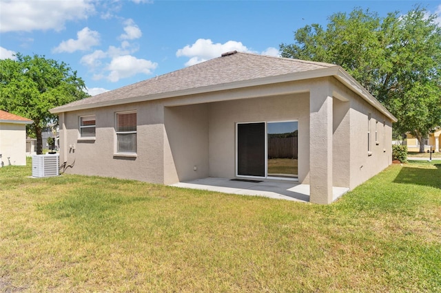 back of property with a lawn, a patio area, stucco siding, and roof with shingles