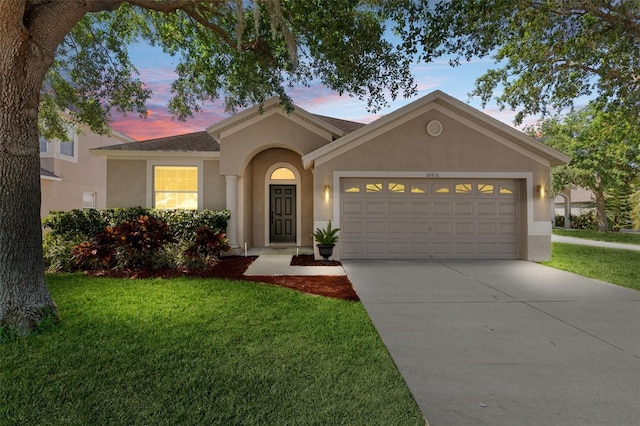 view of front of home featuring an attached garage, stucco siding, a yard, and concrete driveway