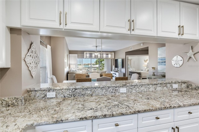 425 150th Ave Unit 2301, Madeira Beach, FL 33708 - kitchen featuring white cabinetry, open floor plan, and light stone counters