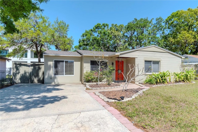 single story home with concrete driveway, a front lawn, and fence