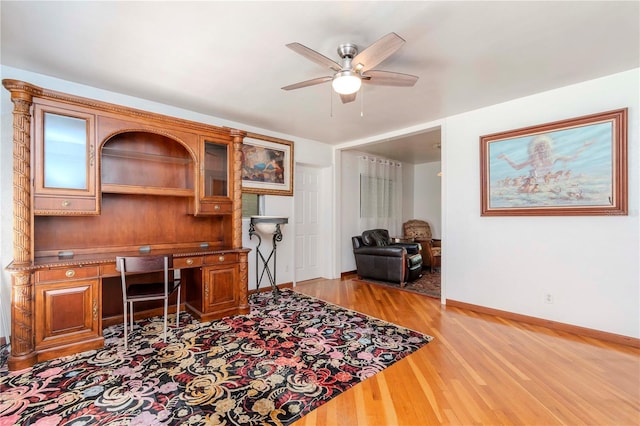 home office featuring a ceiling fan, baseboards, and light wood-type flooring
