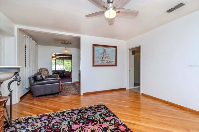 living area with a ceiling fan, visible vents, baseboards, and light wood-type flooring