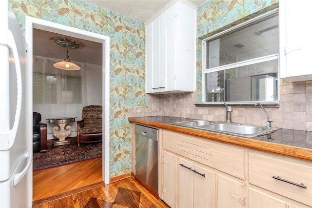 kitchen featuring dishwasher, light wood finished floors, wallpapered walls, and a sink