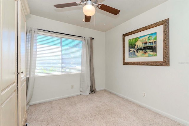 empty room with ceiling fan, light carpet, and baseboards