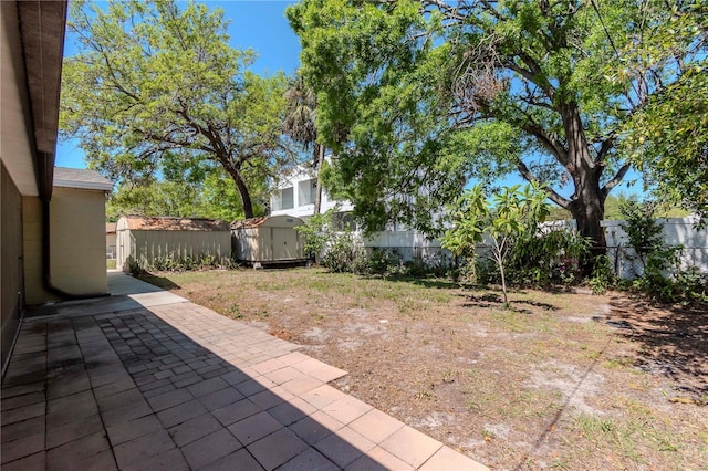 view of yard featuring an outdoor structure, a storage shed, a patio, and a fenced backyard