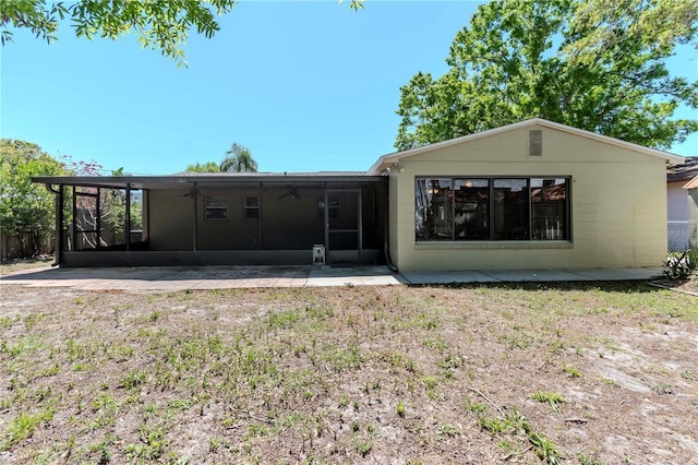 back of property featuring a sunroom, ceiling fan, and concrete block siding