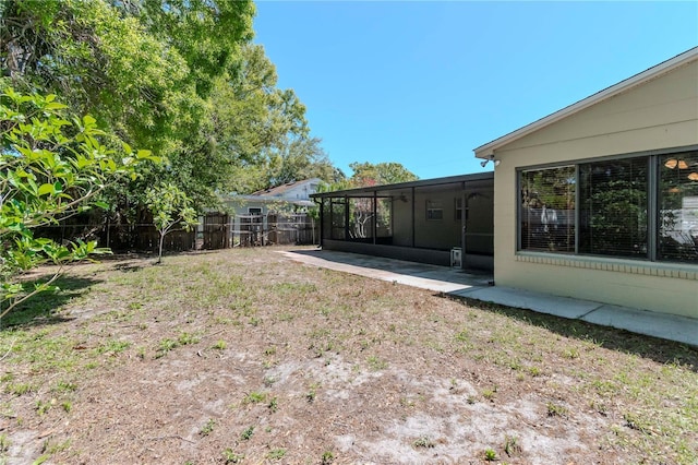 view of yard with a fenced backyard, a patio, and a sunroom