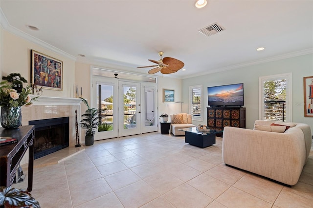 living area with a tiled fireplace, visible vents, a healthy amount of sunlight, and light tile patterned flooring