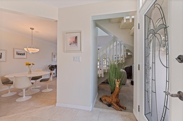 entryway with light tile patterned flooring, baseboards, ornamental molding, and stairs