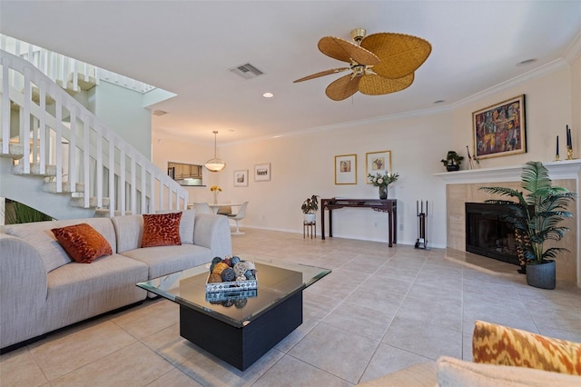 living room with stairs, ornamental molding, ceiling fan, visible vents, and light tile patterned flooring