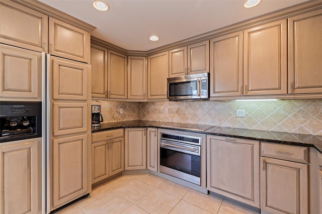 kitchen featuring dark stone countertops, recessed lighting, decorative backsplash, light tile patterned floors, and appliances with stainless steel finishes