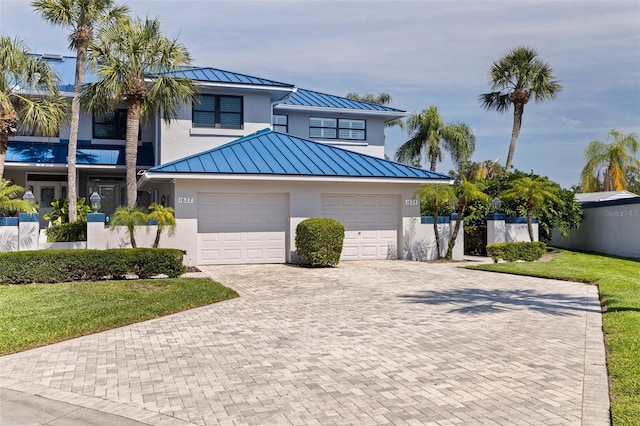 view of front of property with stucco siding, decorative driveway, a standing seam roof, and metal roof