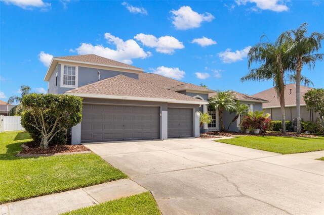 view of front of house with driveway, fence, a front yard, an attached garage, and stucco siding