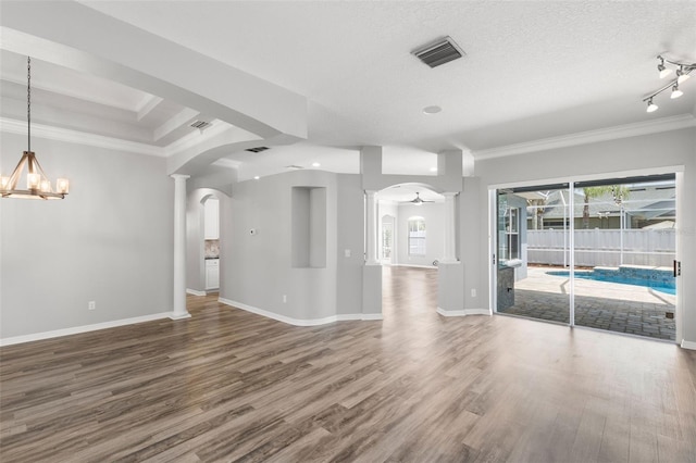 unfurnished living room with wood finished floors, visible vents, crown molding, and arched walkways