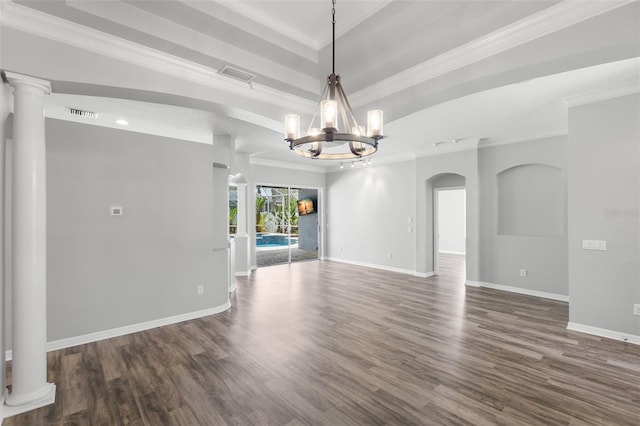 empty room featuring ornamental molding, wood finished floors, a notable chandelier, and baseboards