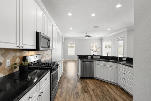 kitchen with dark wood-style floors, a sink, stainless steel appliances, decorative backsplash, and ornamental molding