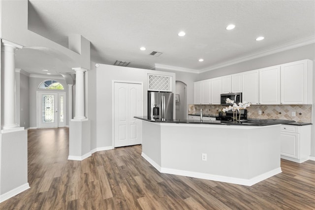 kitchen featuring tasteful backsplash, ornate columns, stainless steel appliances, dark countertops, and visible vents