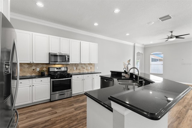 kitchen with crown molding, dark countertops, a sink, and stainless steel appliances