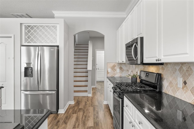 kitchen featuring white cabinetry, arched walkways, appliances with stainless steel finishes, and dark wood-type flooring