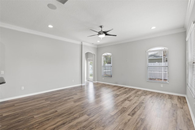 unfurnished room featuring a ceiling fan, arched walkways, a wealth of natural light, and wood finished floors