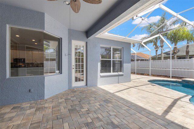 exterior space with a ceiling fan, glass enclosure, and a fenced in pool