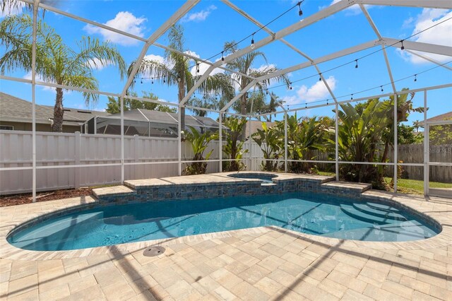 view of swimming pool with a patio, a fenced in pool, a fenced backyard, an in ground hot tub, and glass enclosure
