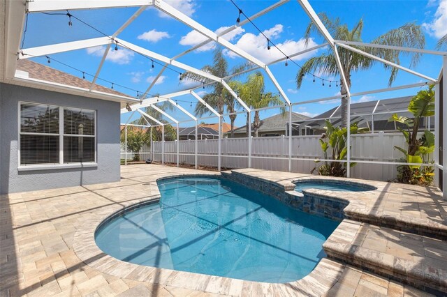 view of swimming pool with a pool with connected hot tub, a patio, glass enclosure, and fence