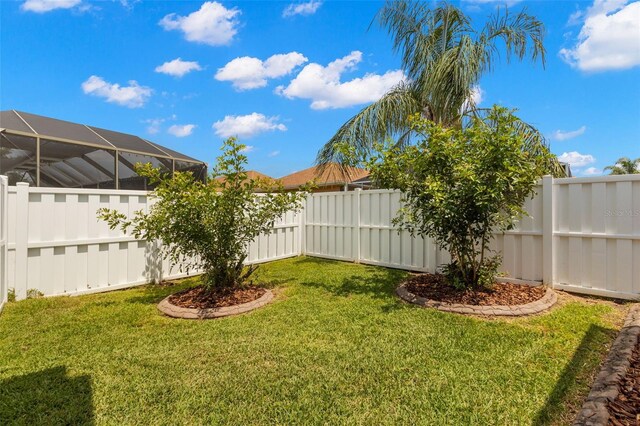 view of yard with glass enclosure and a fenced backyard