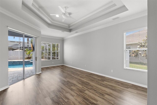 unfurnished room with a tray ceiling, crown molding, a ceiling fan, baseboards, and wood finished floors