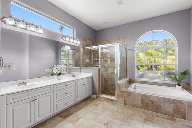 bathroom with a garden tub, a sink, a wealth of natural light, and visible vents