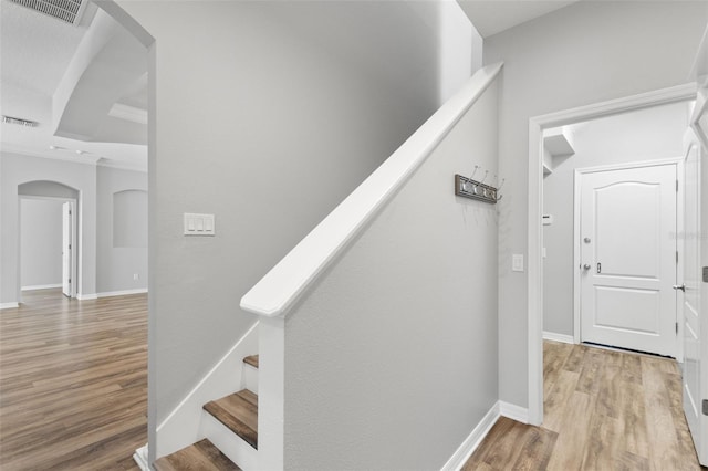 stairway featuring baseboards, visible vents, arched walkways, and wood finished floors