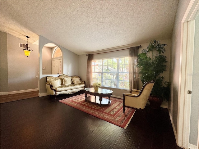 living room featuring a textured ceiling, visible vents, hardwood / wood-style flooring, and arched walkways