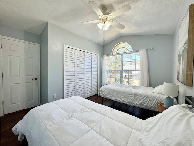 bedroom featuring a textured ceiling, dark wood-style flooring, a closet, and vaulted ceiling
