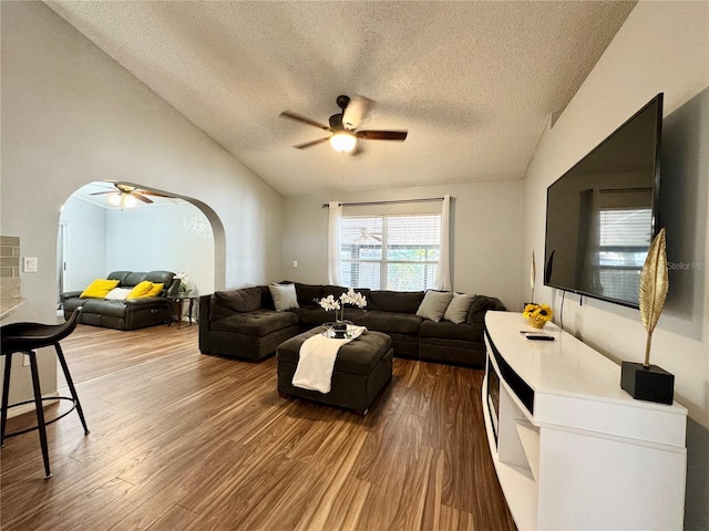 living room featuring arched walkways, ceiling fan, wood finished floors, and a textured ceiling