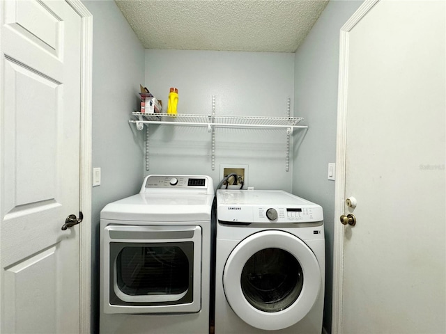 washroom featuring a textured ceiling, separate washer and dryer, and laundry area