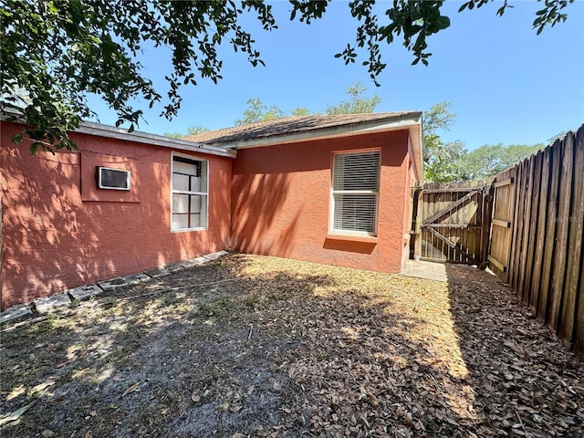 rear view of property featuring a gate, fence, and stucco siding