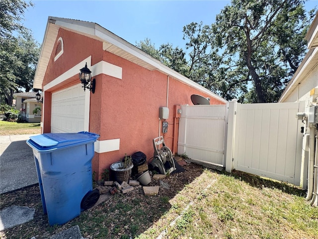 view of side of property with a gate, fence, and stucco siding