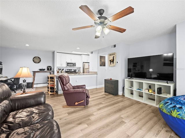 living room featuring visible vents, a textured ceiling, light wood-style floors, and ceiling fan