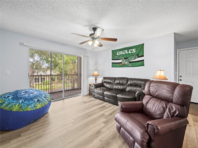 living area with a ceiling fan, a textured ceiling, and wood finished floors