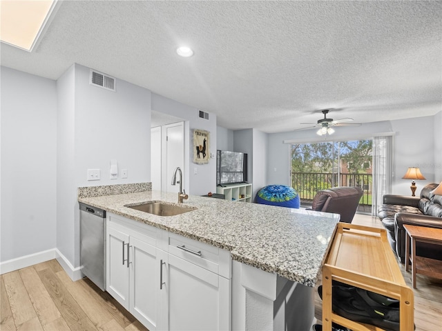 kitchen featuring a sink, light wood-style floors, dishwasher, a peninsula, and visible vents