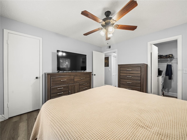 bedroom featuring dark wood-type flooring, ceiling fan, visible vents, and a closet