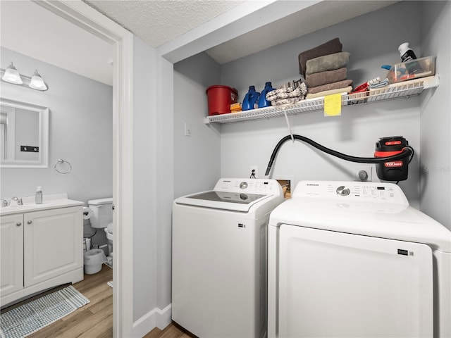 laundry area featuring independent washer and dryer, laundry area, a textured ceiling, light wood-style flooring, and baseboards