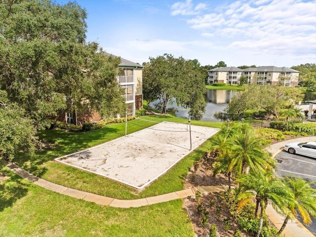 view of property's community with volleyball court, a water view, a yard, and uncovered parking