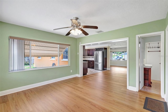 3065 Merrill Ave, Clearwater, FL 33759 - unfurnished living room featuring light wood-type flooring, ceiling fan, baseboards, and a textured ceiling